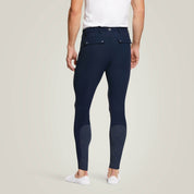 Back view of a male model wearing the Navy Ariat Men's Tri Factor Knee Patch Breeches on a plain background