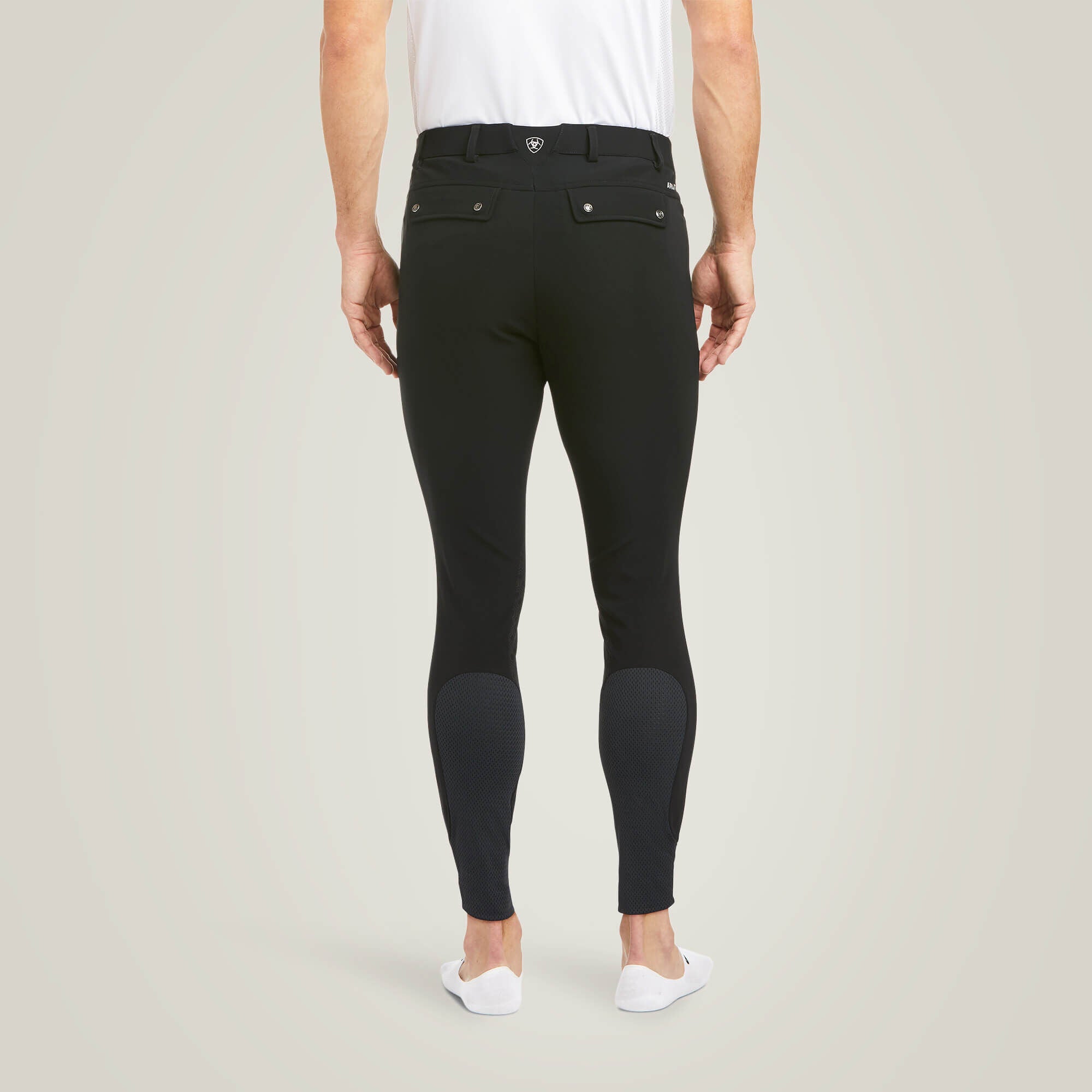 Back view of a male model wearing the Black Ariat Men's Tri Factor Knee Patch Breeches on a plain background