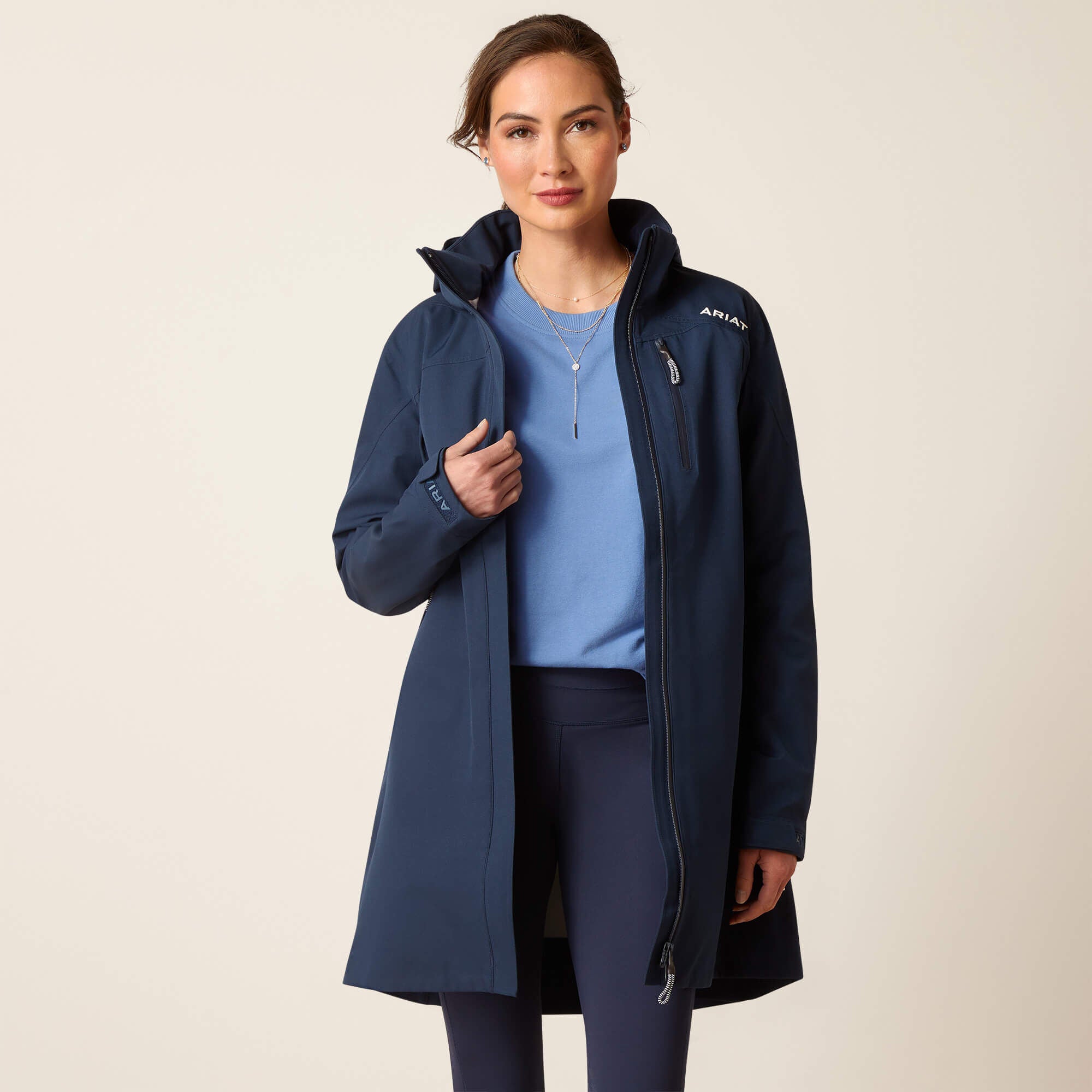 Front view of a female model wearing the Navy Ariat Coastal Long H2O Parka on a plain background