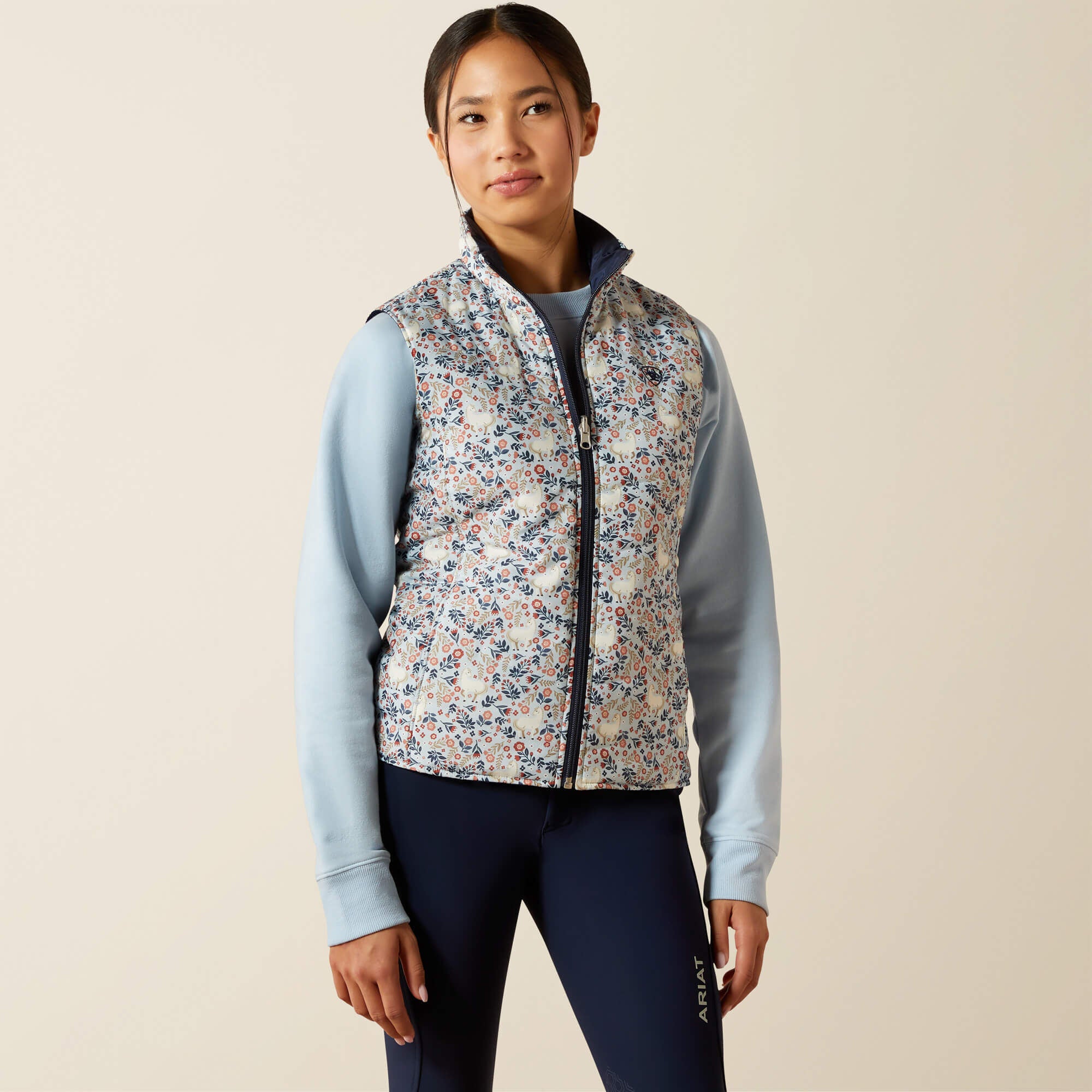 Front view of a young female model wearing the Posey Pony Print Ariat Youth Bella Reversible Insulated Vest on a plain background