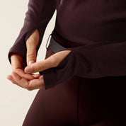 Close-up view of a female model showing the thumbholes on the Chocolate Plum Ariat Cheviot 1/4 Zip Long Sleeve Baselayer on a plain background