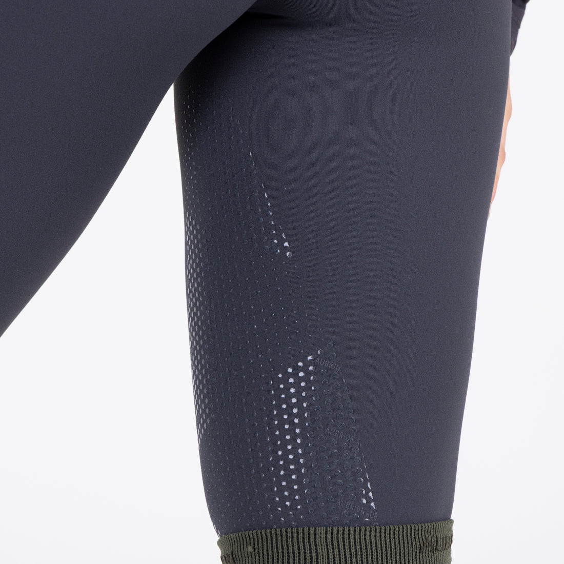Close-up view of the silicone grip on the Aubrion React Winter Knee Patch Riding Tights on a plain background