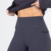 Front view of a female model wearing the Charcoal Aubrion React Winter Knee Patch Riding Tights and showing the wide waistband on a plain background