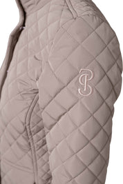Tan quilted jacket with zipper cover and short collar shown, with embroidered logo on shoulder on model on plain white background