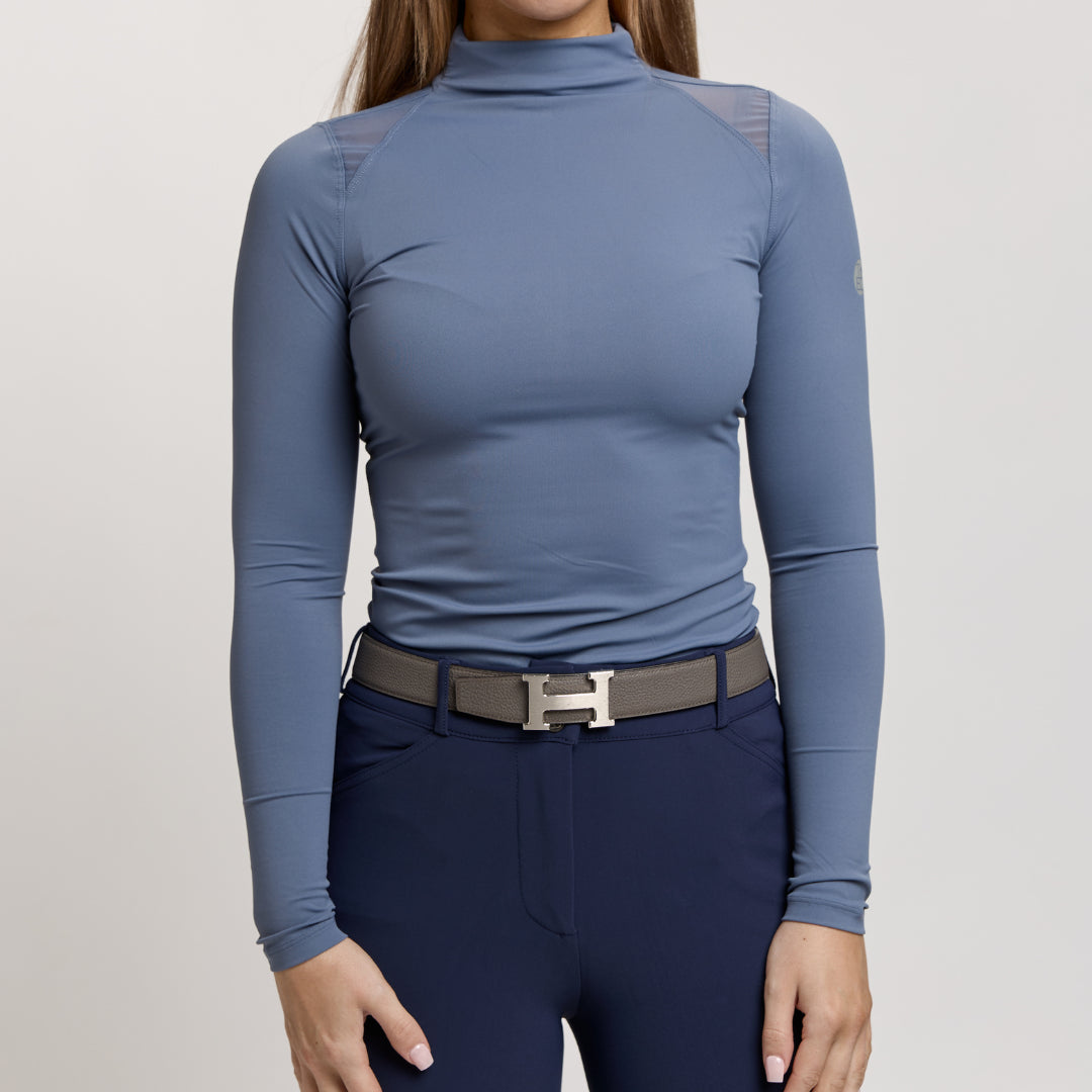 Front view of a female model wearing the Denim TKEQ Chloe High Collar Technical Top on a plain background