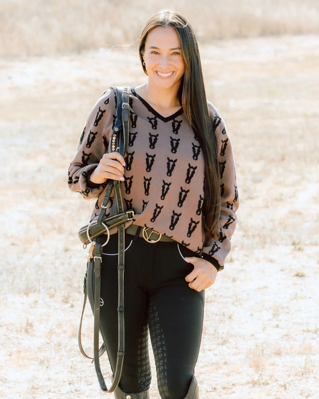 Front view of a female model wearing the Saddle/Black Deinhardt Designs Varsity Sweater while standing outside