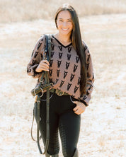 Front view of a female model wearing the Saddle/Black Deinhardt Designs Varsity Sweater while standing outside