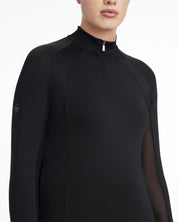 Close-up view of a model wearing the black LeMieux Halle Lightweight Base Layer on a white background