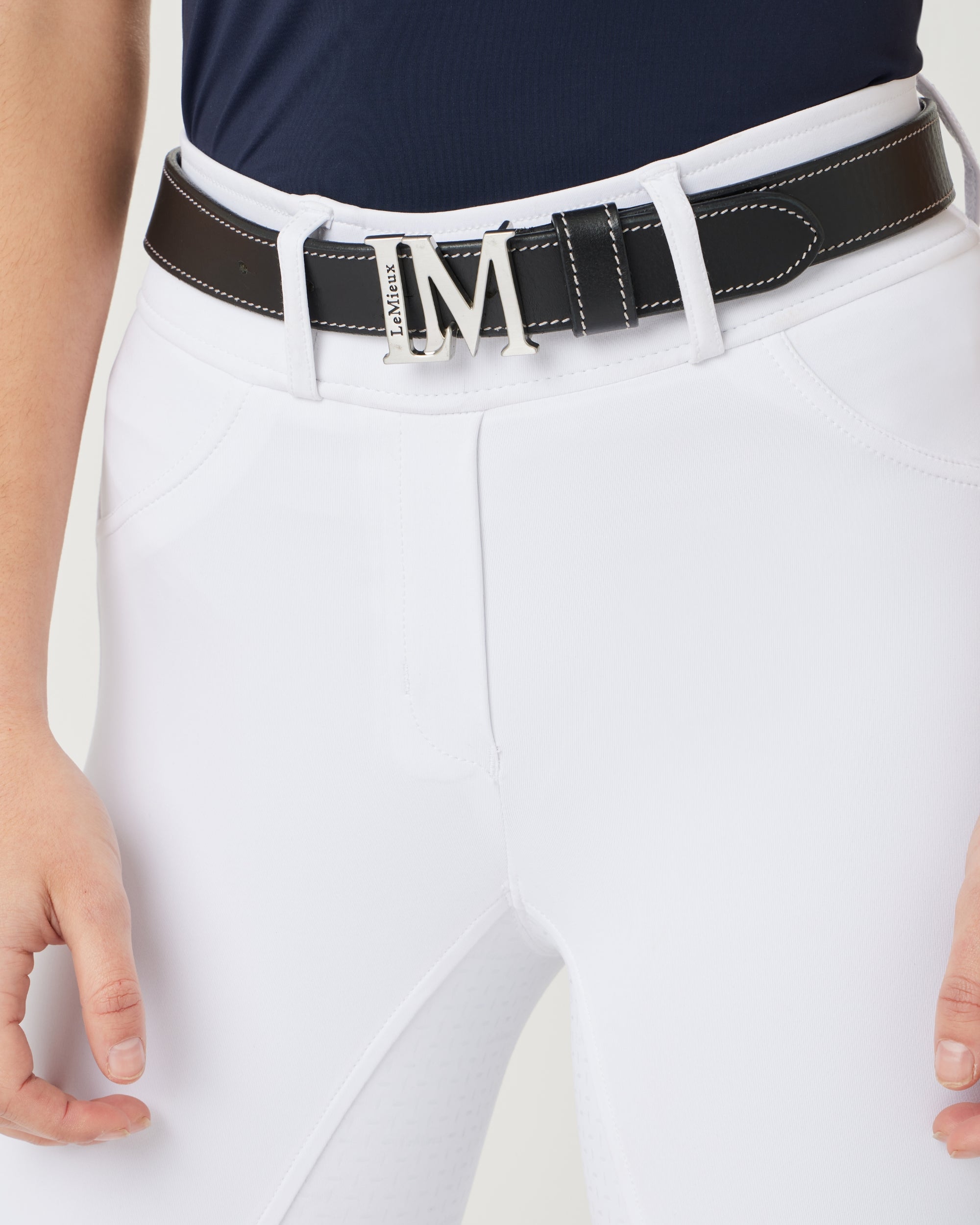 Front view of a female model wearing the Black LeMieux Monogram Belt over white breeches