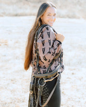 Side view of a female model wearing the Saddle/Black Deinhardt Designs Varsity Sweater while standing outside