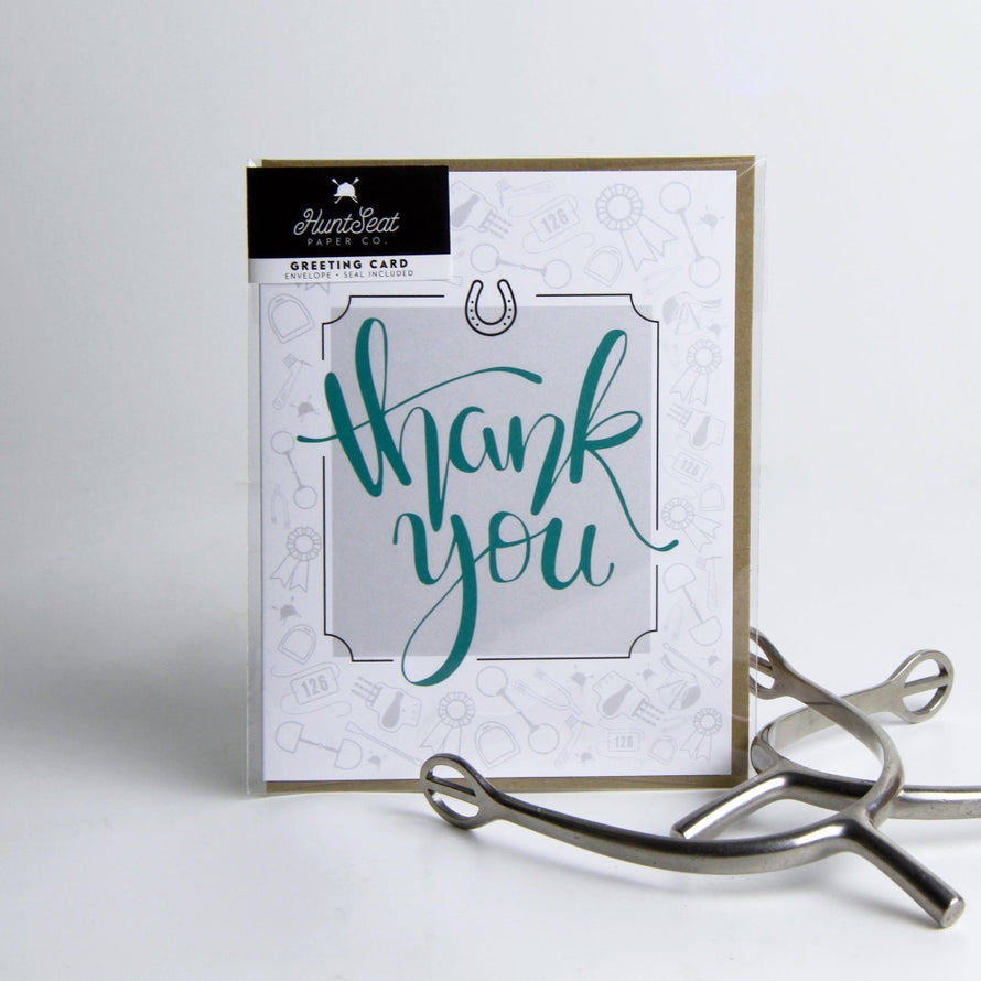 Front view of the Thank you Hunt Seat Paper Co. Greeting Card next to a pair of spurs on a plain background