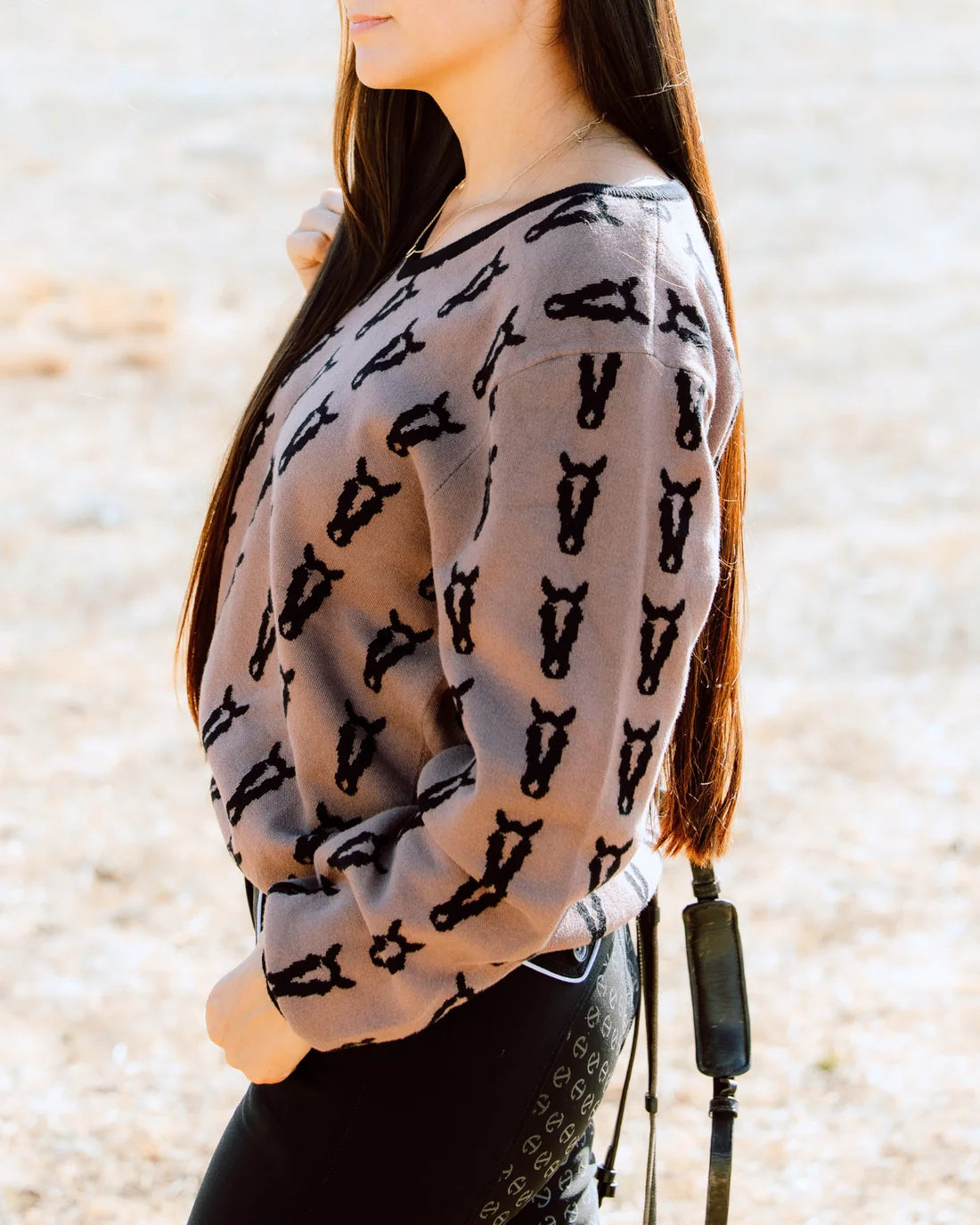 Side view of a female model wearing the Saddle/Black Deinhardt Designs Varsity Sweater while standing outside