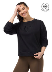 Front view of a female model wearing the Black Kerrits Cozy Crest Plush Fleece Sweatshirt on a plain background