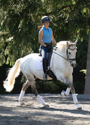 Rider wearing a blue sleeveless riding shirt riding a white horse