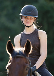 Woman wearing Kerrits Printed Sport Tank in Mocha brown riding a horse wearing a helmet