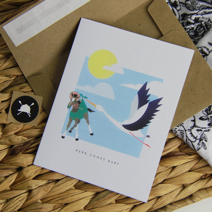 Front view of the Here Comes Baby Hunt Seat Paper Co. Greeting Card with its envelope