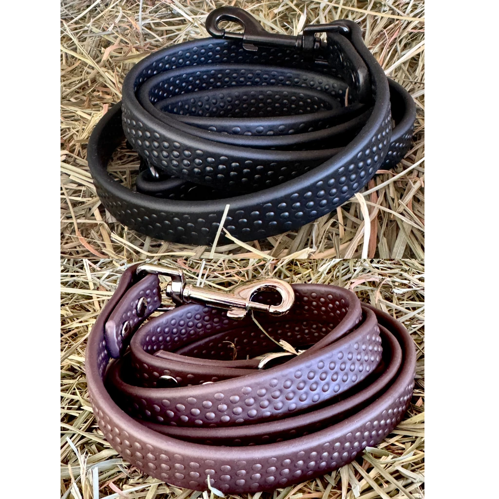 View of a black and a brown PRO4MANCE Com4rt Grip Dog Leash on hay