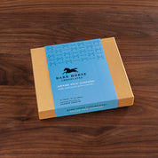 View of the 16 piece Harbor Sweets Chocolate Grand Prix Jumpers gift box on a wood background