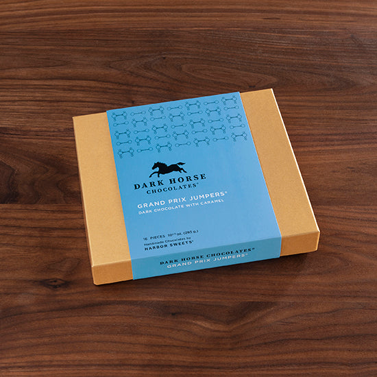 View of the 16 piece Harbor Sweets Chocolate Grand Prix Jumpers gift box on a wood background