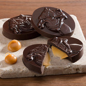 View of the Harbor Sweets Chocolate Grand Prix Jumpers on a tile coaster and wood background