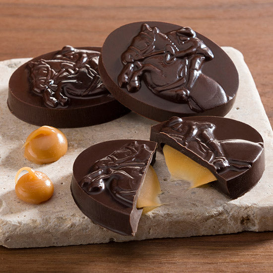 View of the Harbor Sweets Chocolate Grand Prix Jumpers on a tile coaster and wood background