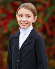 Front view of a young female model wearing the Black Kerrits Kids Stretch Competitor Show Coat on a colorful background