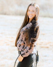 Side view of a female model wearing the Saddle/Black Deinhardt Designs Varsity Sweater while standing outside