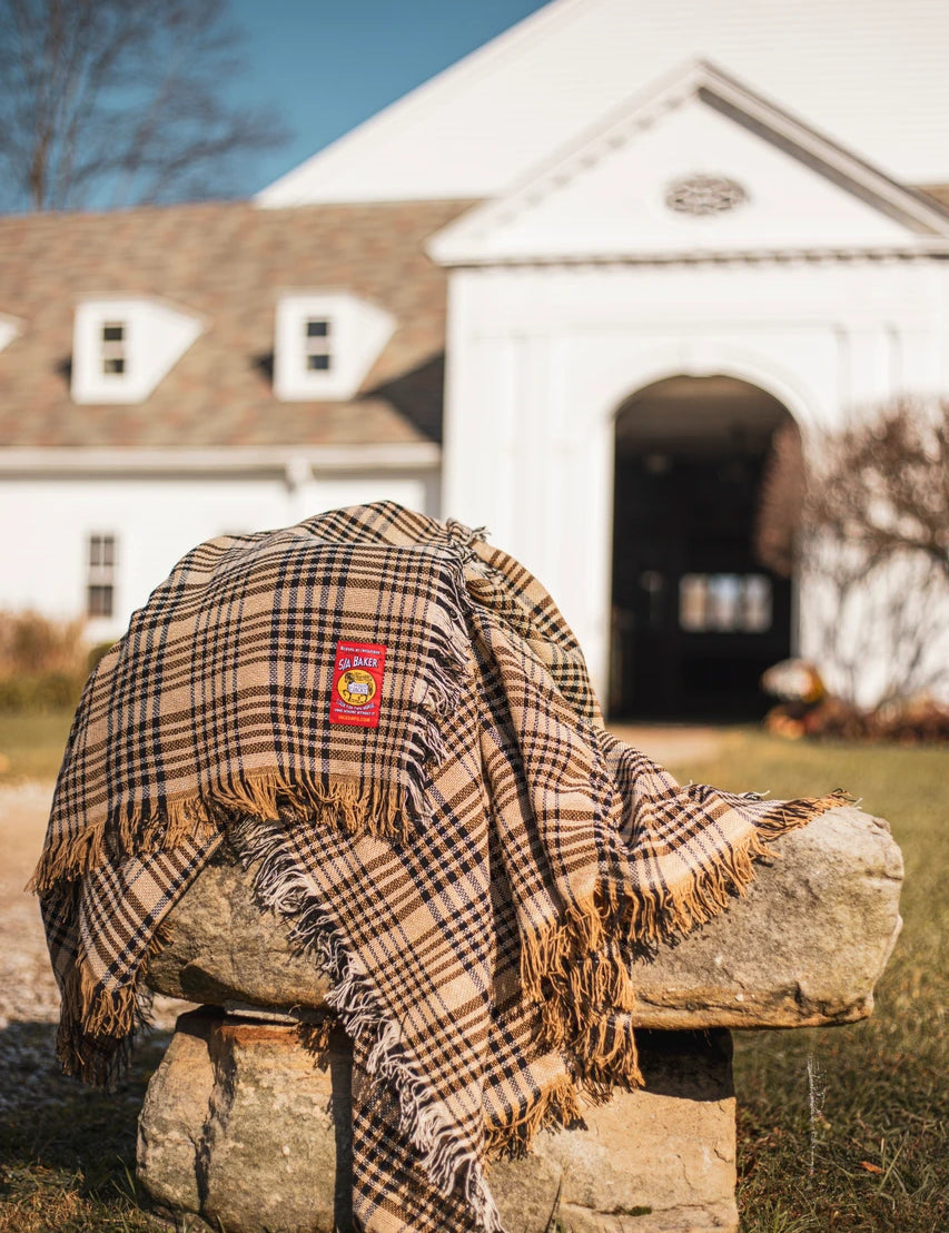 A Baker Cotton Plaid Throw Blanket on a rock outside