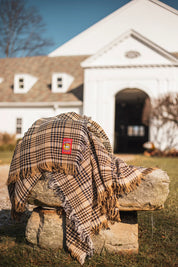 View of the 5/A Baker Cotton Plaid Throw Blanket on a rock outside