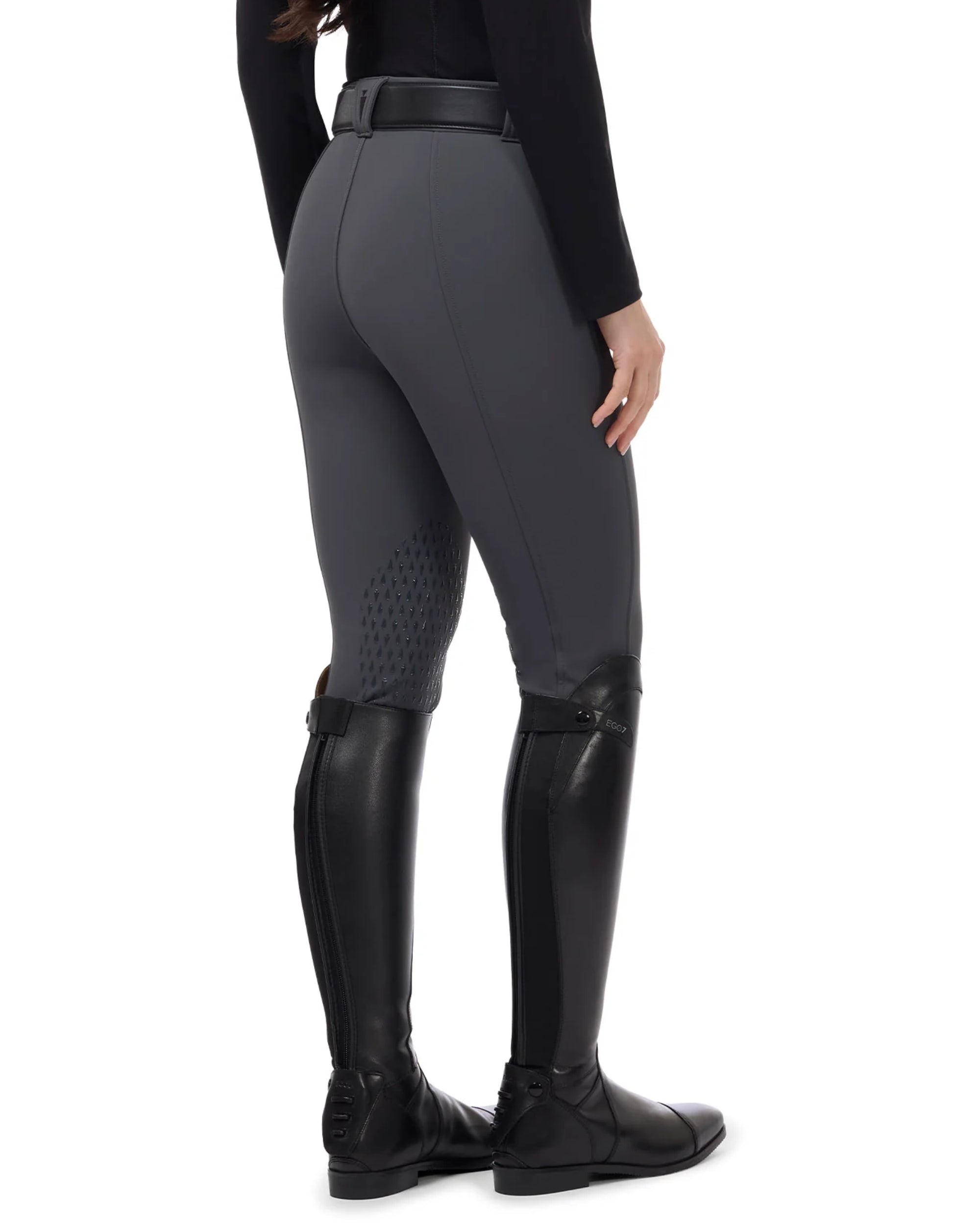 Angled back view of a female model wearing the Carbon Kerrits 3-Season Tailored Knee Patch Breech on a white background