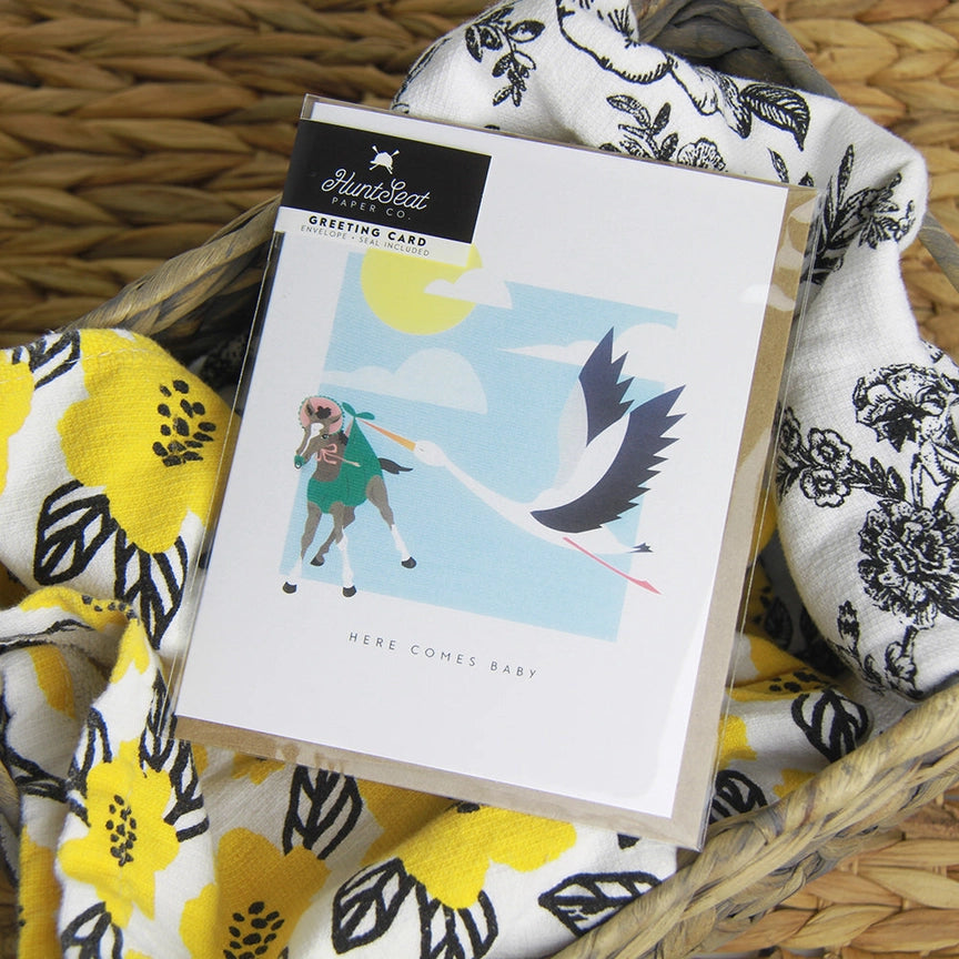 Front view of the Here Comes Baby Hunt Seat Paper Co. Greeting Card in its packaging