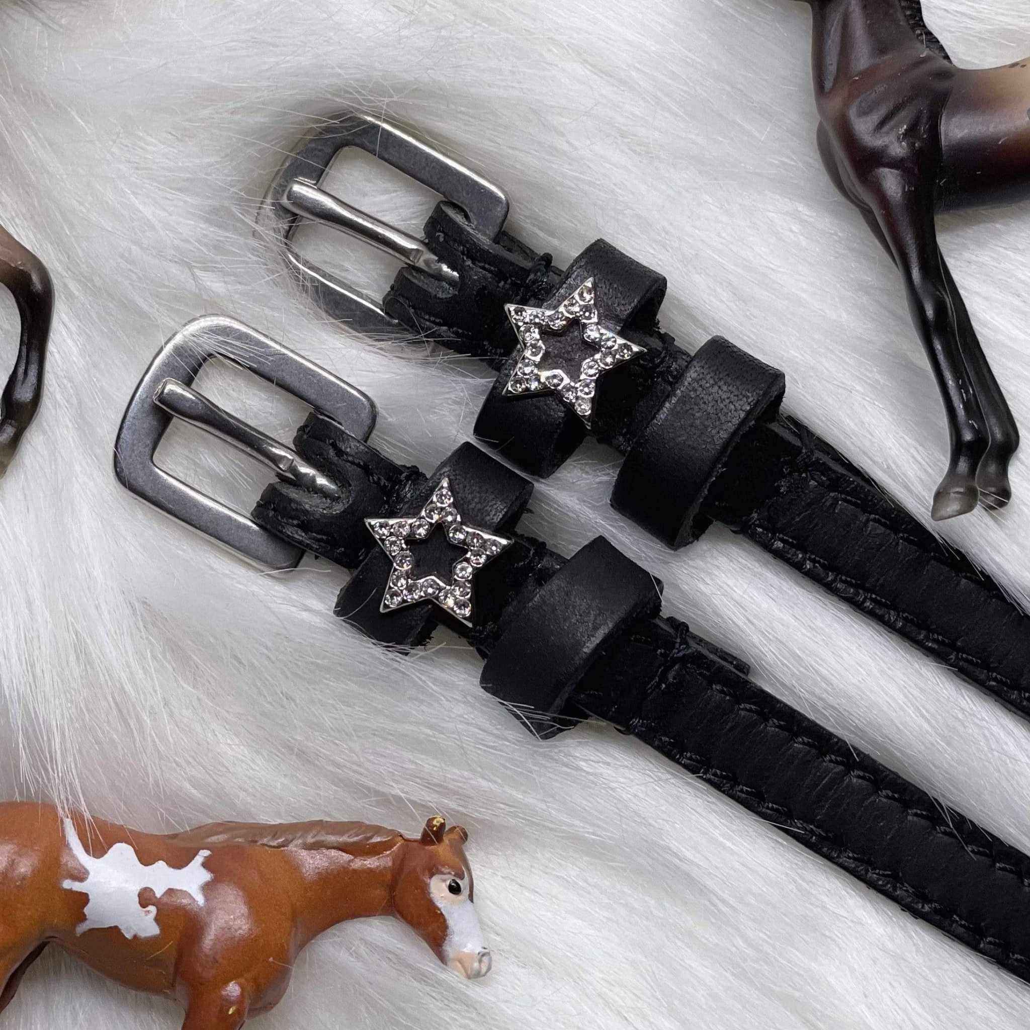 View of the sparkly star Mane Jane Spur Straps on a white fur background with horse figurines