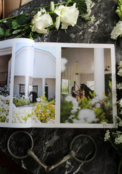 View of the open Stable Style Book-Volume III on a marble and flower background