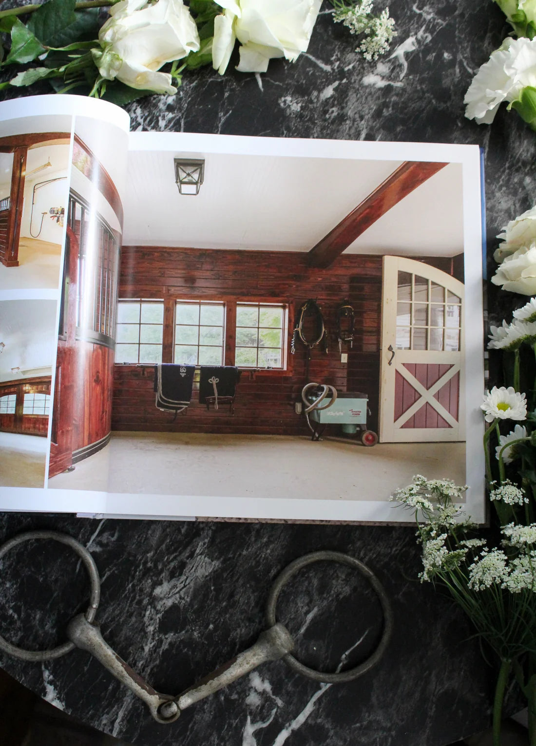 View of the open Stable Style Book-Volume III on a marble and flower background