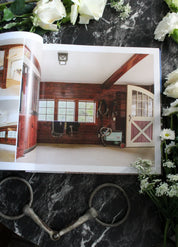View of the open Stable Style Book-Volume III on a marble and flower background