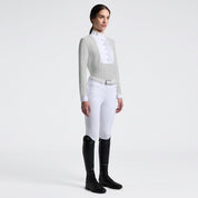 Full body angled front view of a female model wearing the gray Cavalleria Toscana Long Sleeve Jacquard Jersey Competition Shirt with white breeches on a plain background