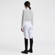 Full body angled back view of a female model wearing the gray Cavalleria Toscana Long Sleeve Jacquard Jersey Competition Shirt with white breeches on a plain background