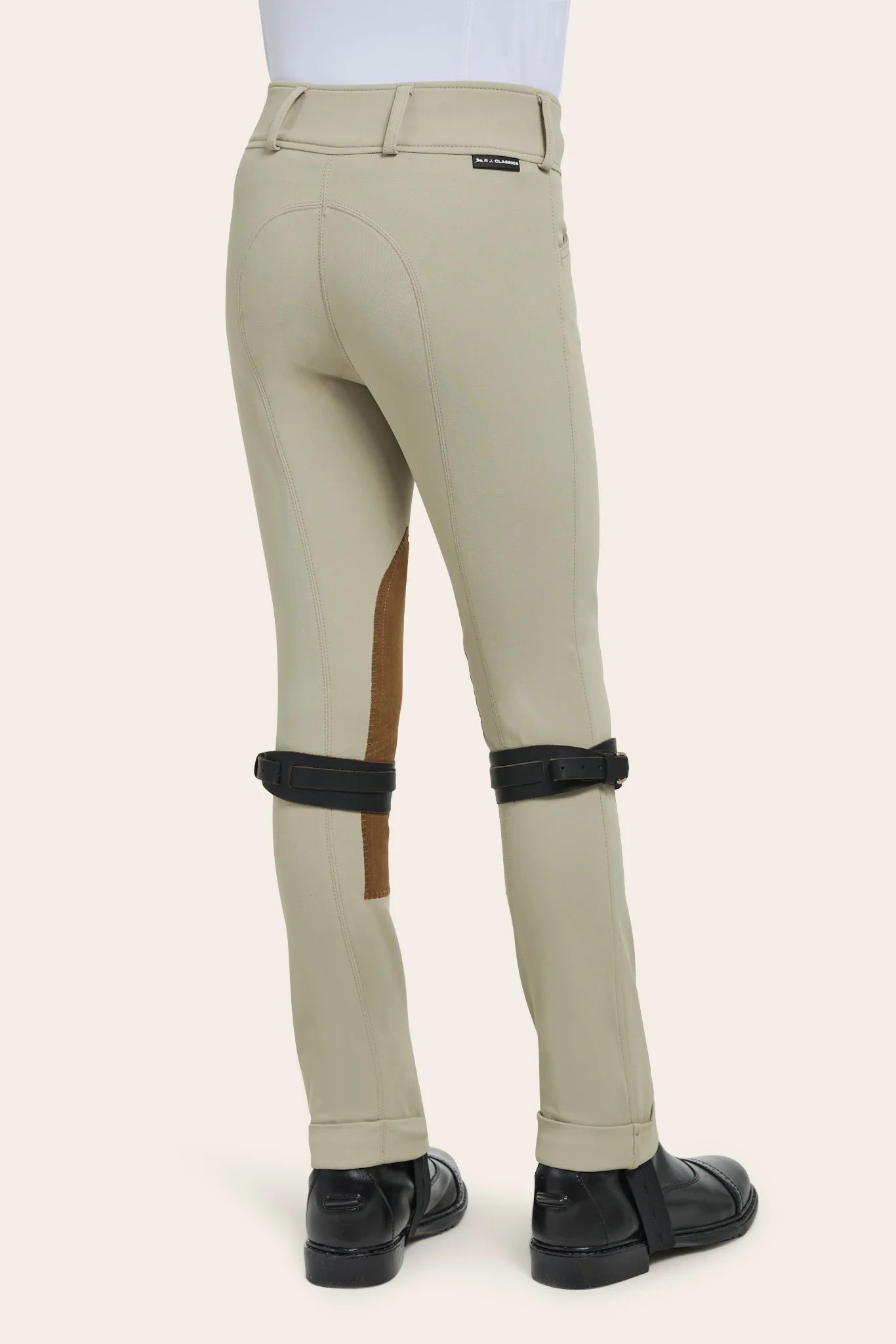 Beige riding pants with brown patch and black knee pads on a white background