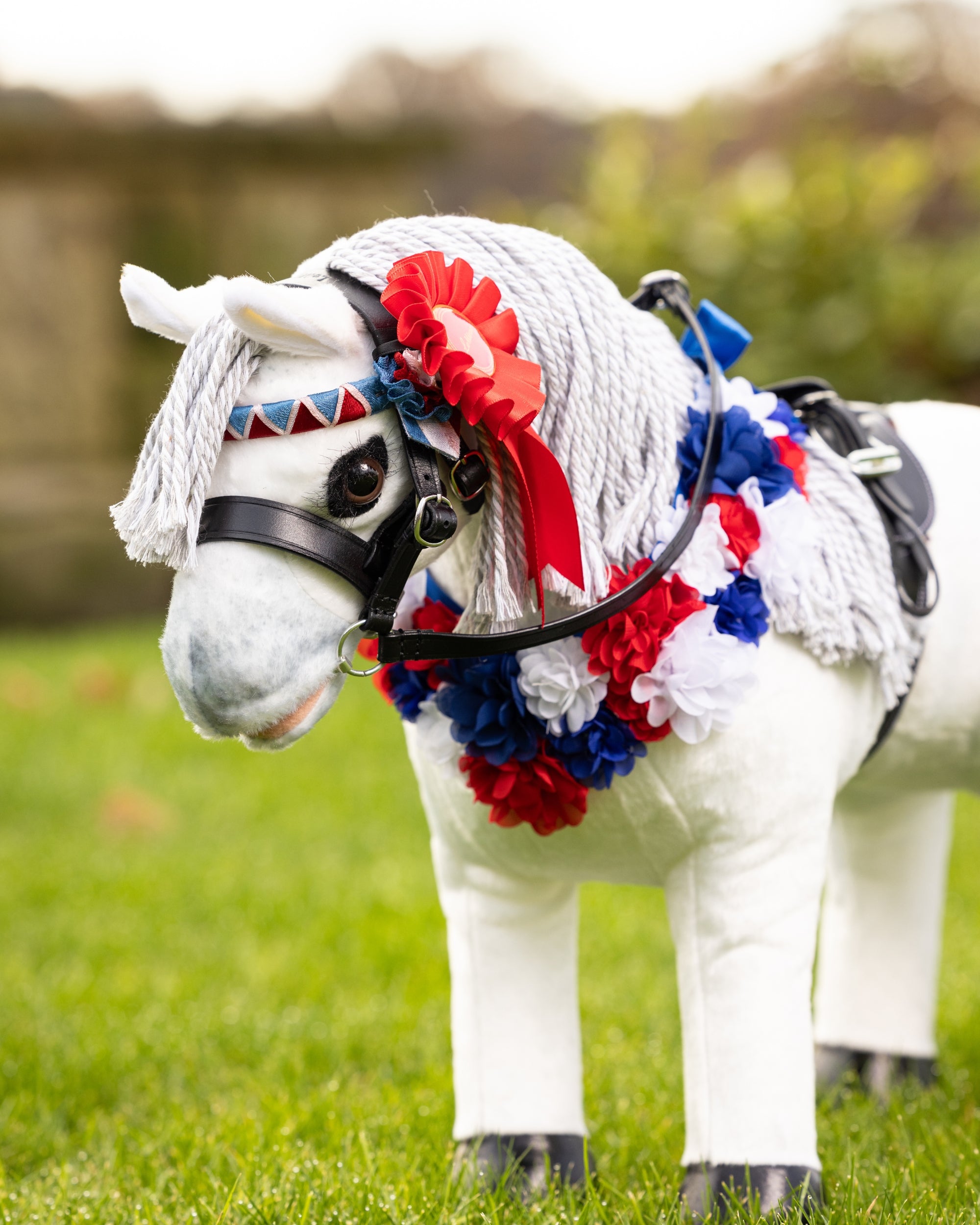 View of a gray horse wearing the red ribbon from the LeMieux Toy Pony Rosette Pack while standing outside
