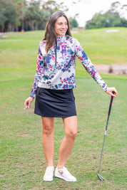 Front view of a model wearing the Kastel Amethyst Watercolor Floral Scuba 1/2 Zip Pullover outdoors on a golf course