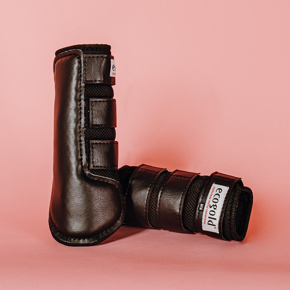 View of a pair of black Ecogold Breathable Exercise Horse Boots on a pink background