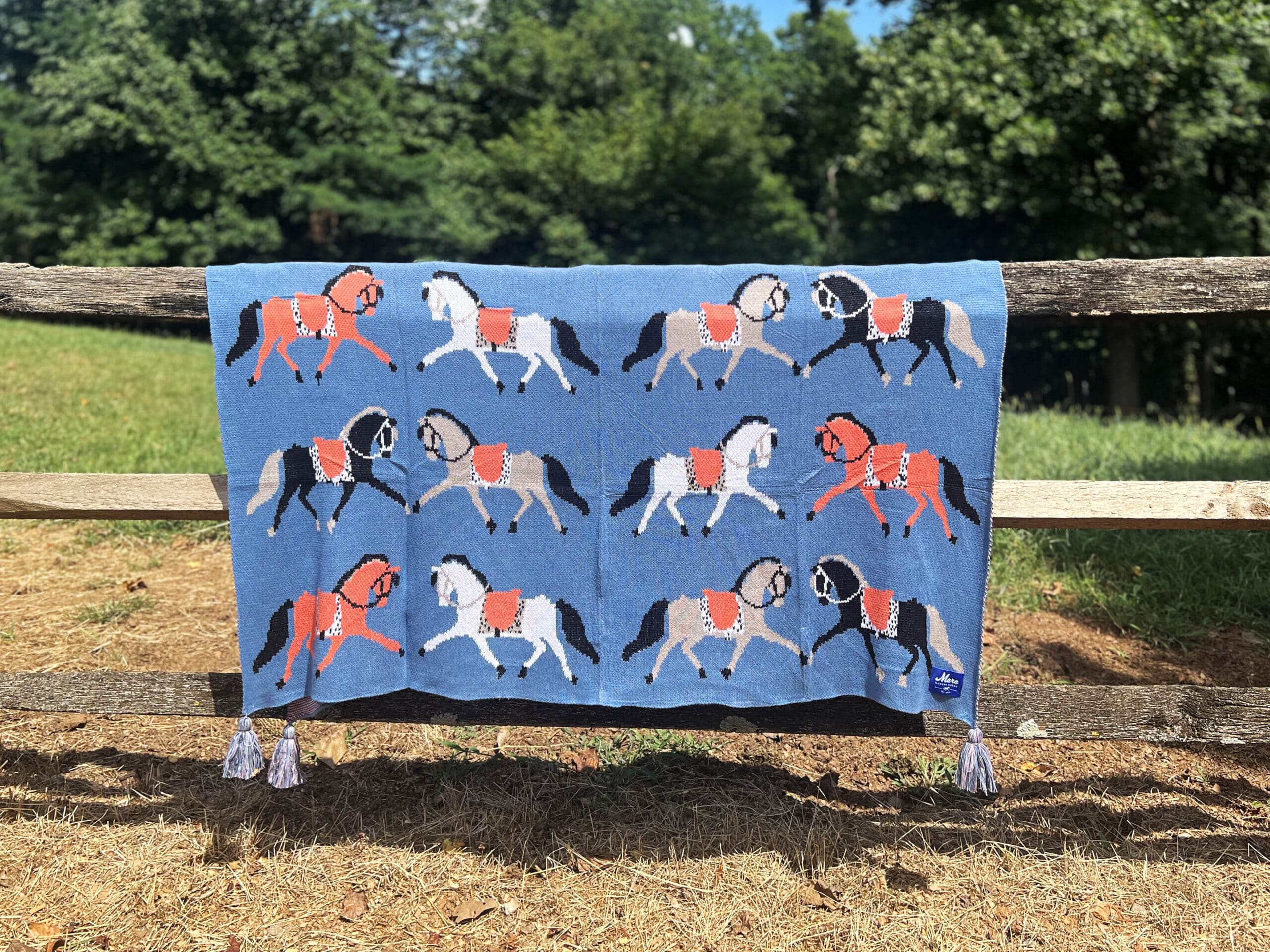 View of the Fancy Horses Mare Modern Goods Blanket draped over a raw wood fence outside