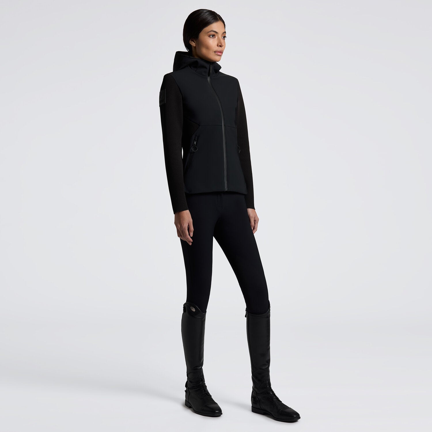 Black full zip softshell jacket with hood and shoulder logo shown on model in front of plain white background