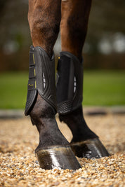 Side view of a horse wearing a pair of LeMieux MIMsafe XC Front Boots while standing in gravel