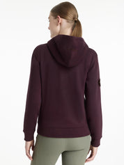 Back view of a female model wearing the Damson LeMieux Elspeth Hoodie on a plain background