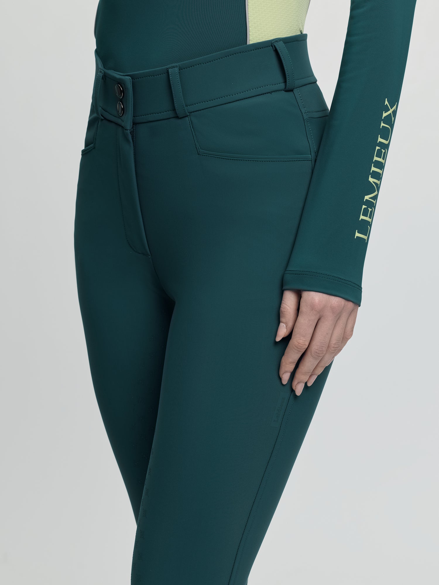 Close-up of LeMieux Isabelle Full Seat Breeches in jungle green showing waistband, belt loops, and front pocket
