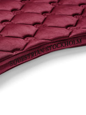 Close-up view of the spine on the Merlot Equestrian Stockholm Velvet Jump Saddle Pad on a plain background