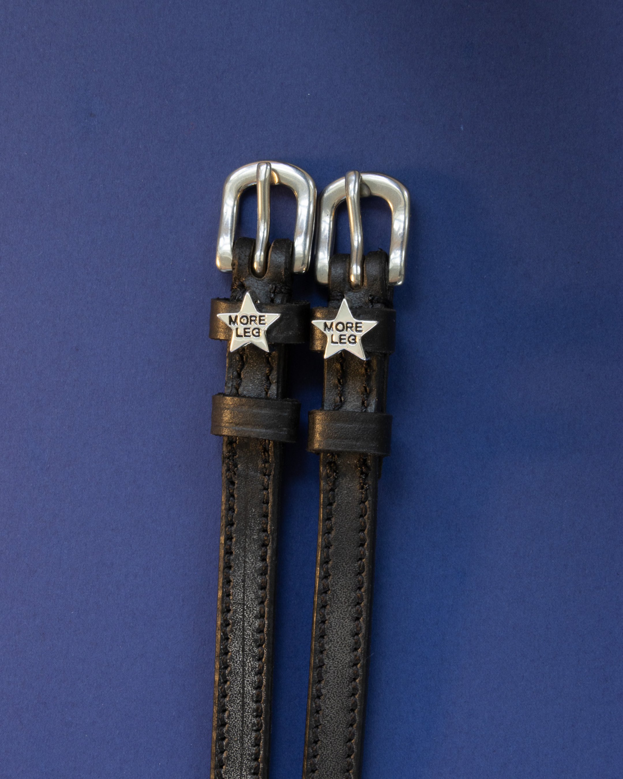 View of the More Leg Mane Jane Spur Straps  on a plain navy background