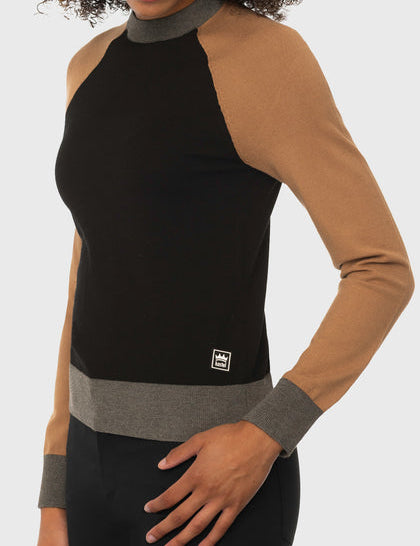 Angled front view of a female model wearing the Kastel Black, Camel, & Charcoal Crewneck Colorblock Sweater on a plain background