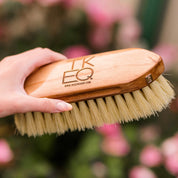 View of a female model holding the TKEQ - TKEQ x SPR Natural Dandy Brush